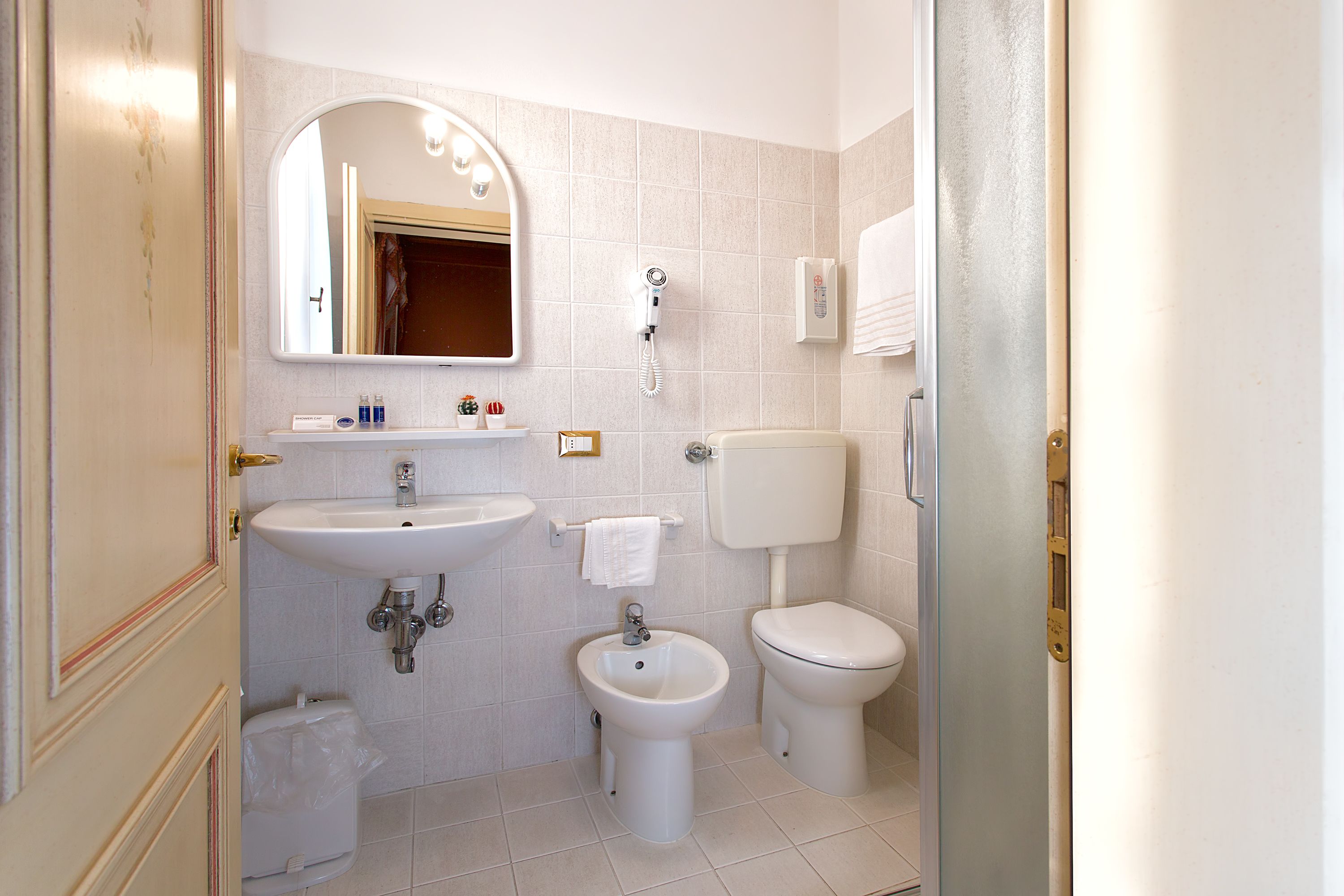 Ein Badezimmer mit Waschbecken, Bidet, Toilette und einem beleuchteten Spiegel.