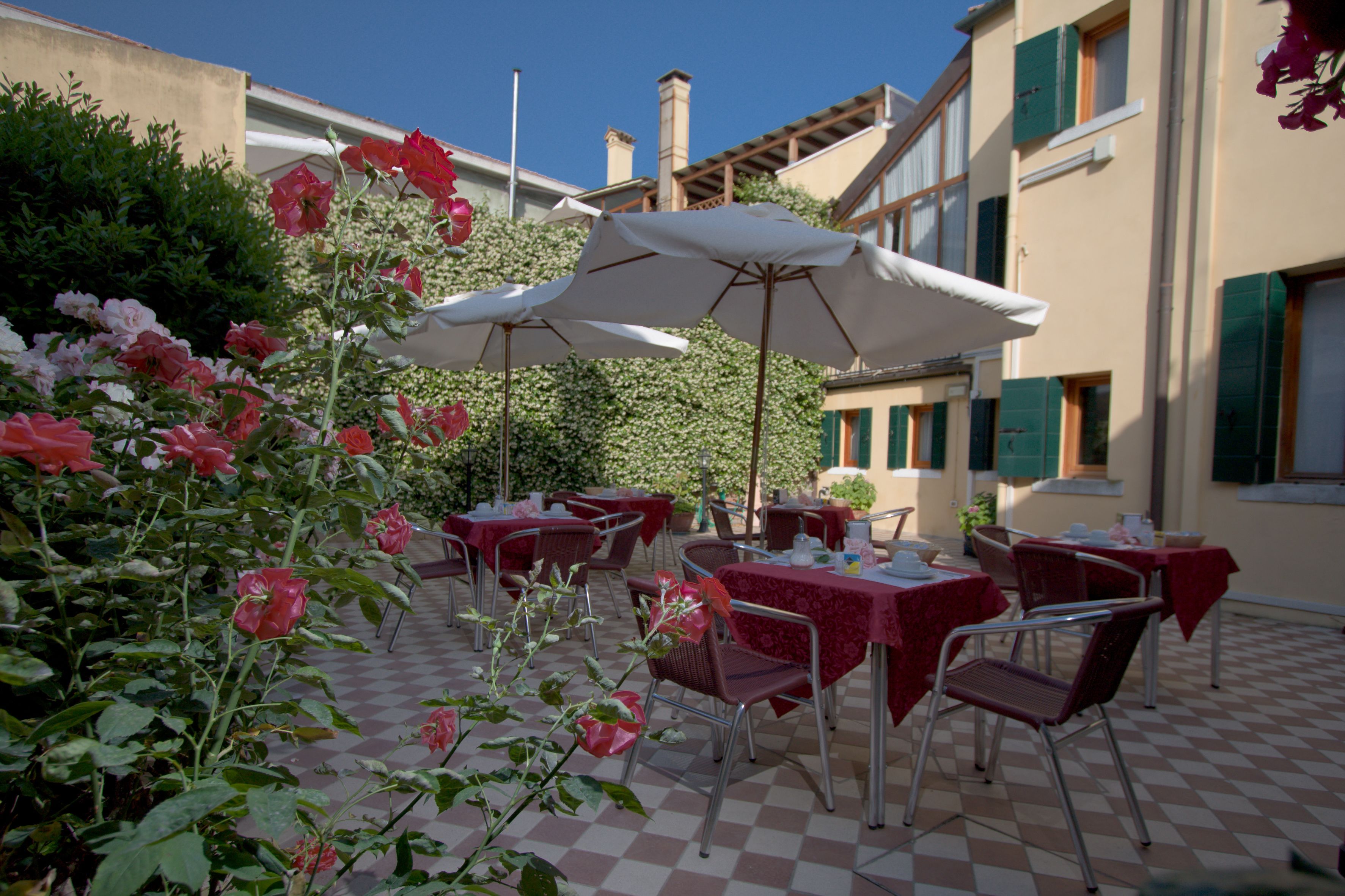 An outdoor cafe with checkered flooring, red tablecloths, and metal chairs.