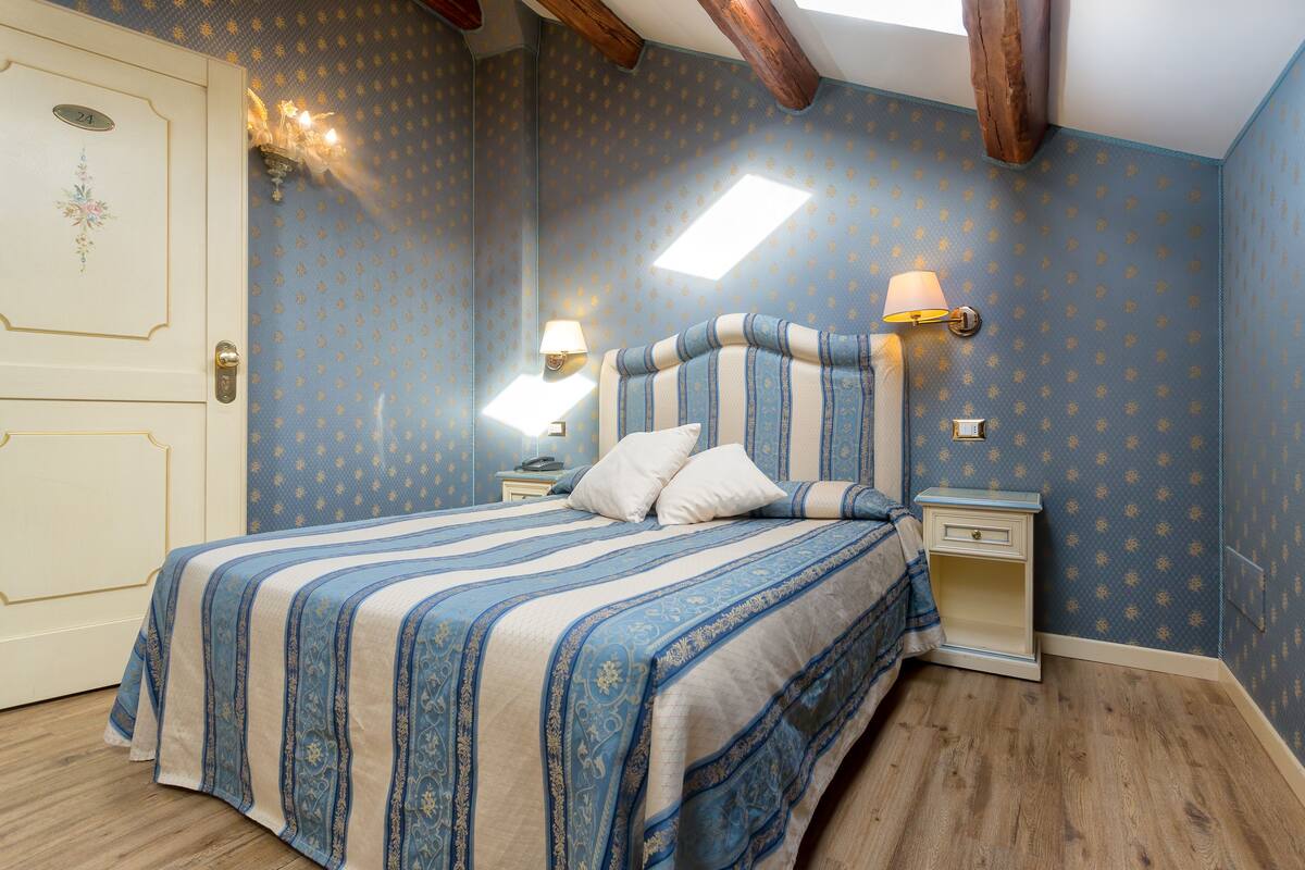 Un dormitorio con una cama, dos mesitas de noche y una puerta.