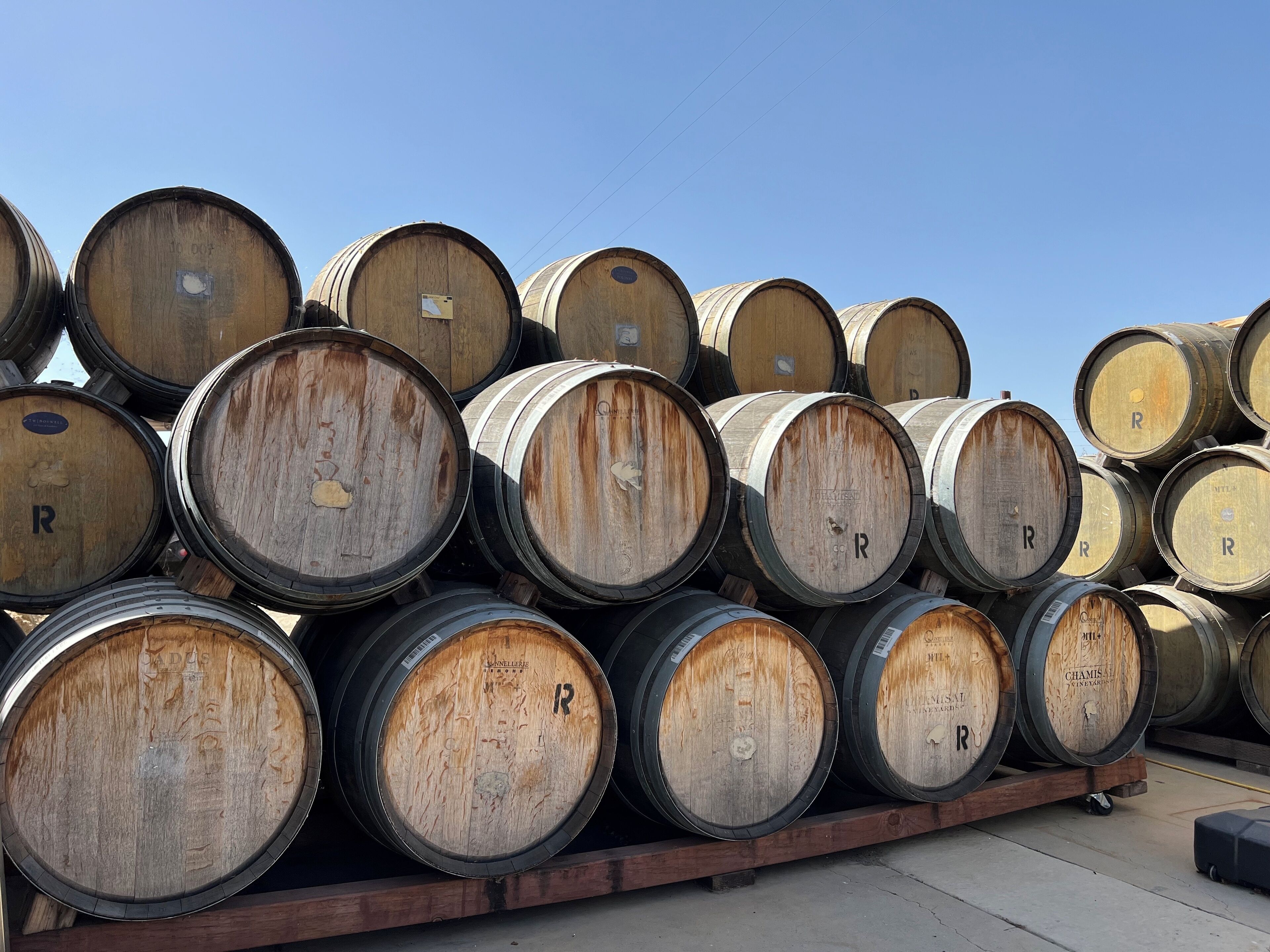 A stack of wooden barrels with the letter "R" on them, arranged on a wooden pallet.