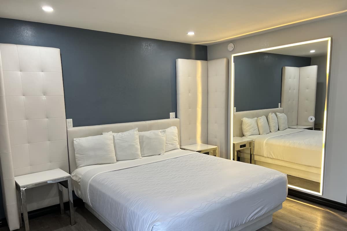 Une chambre à coucher moderne avec un grand lit, une table de chevet, une commode et un miroir.