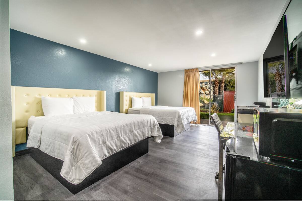 Une chambre d’hôtel avec deux lits, une télévision et une vue sur les palmiers.