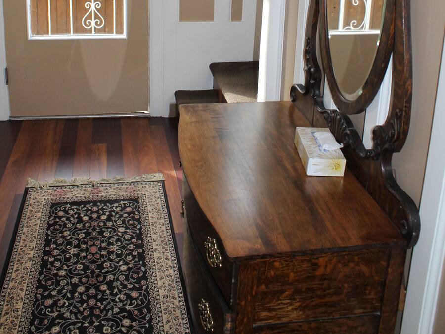 A wooden dresser with a mirror, a patterned rug, and a door leading to a balcony.