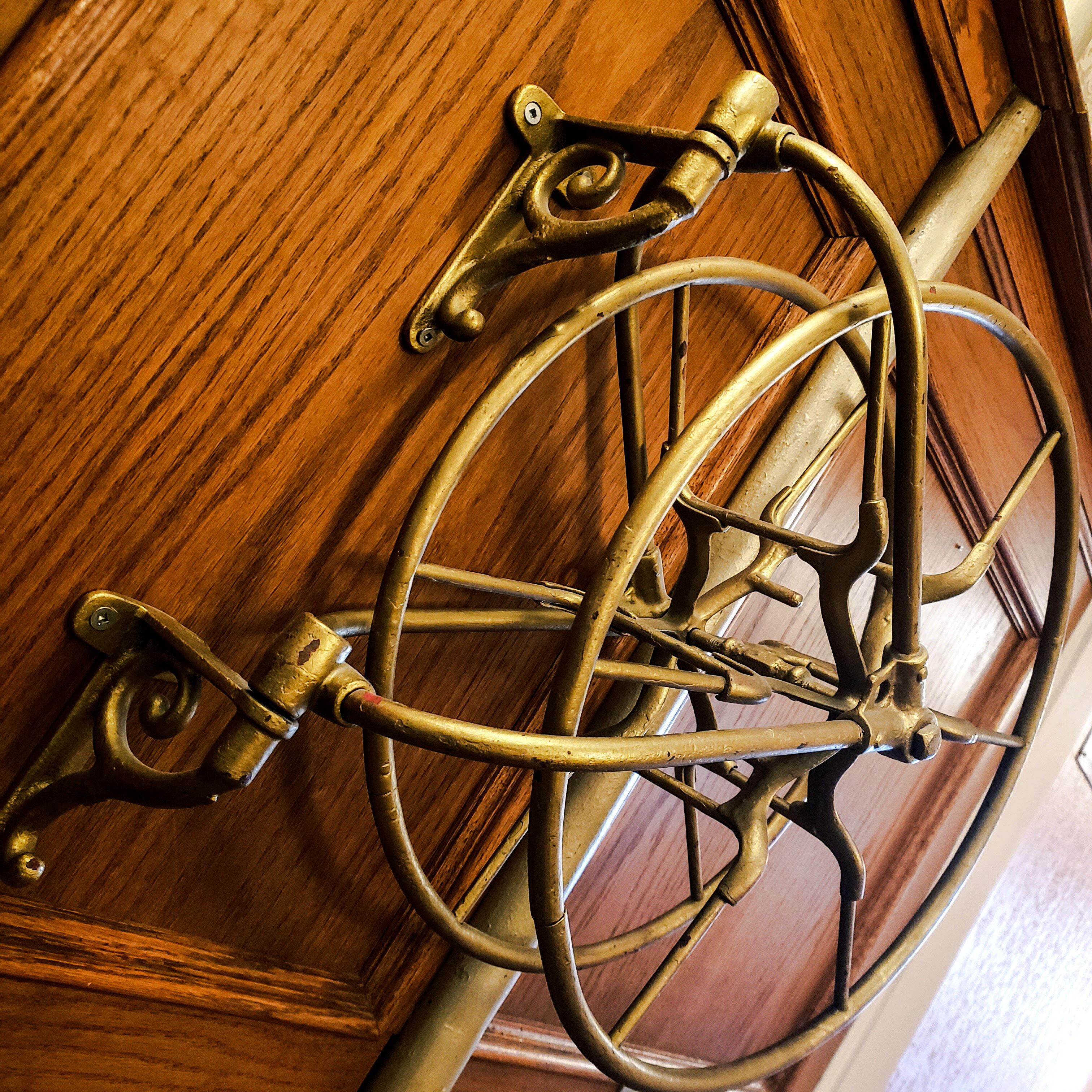 A brass bicycle wheel mounted on a wooden door.