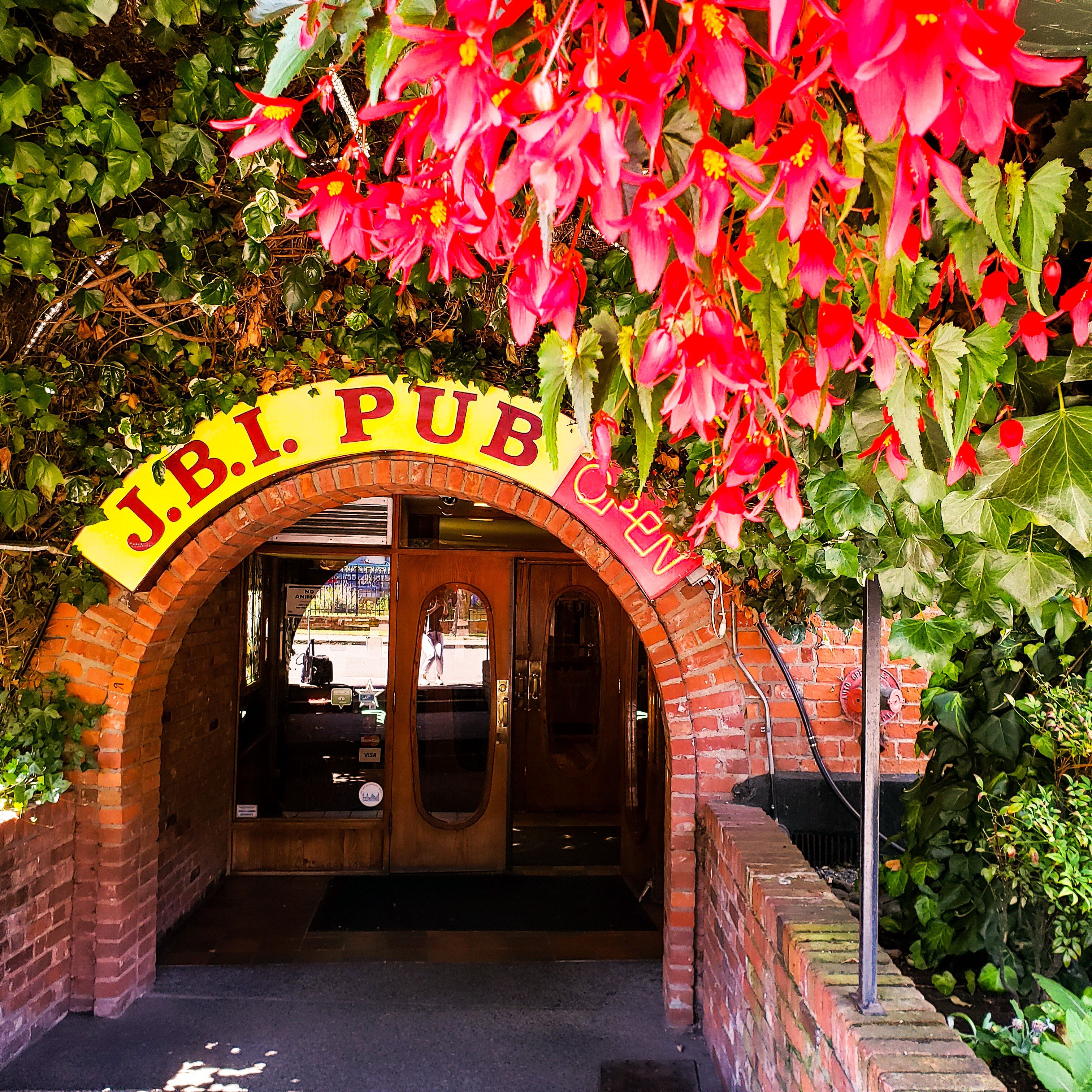 An entrance to J.B.I. Pub with a brick archway and a sign above.