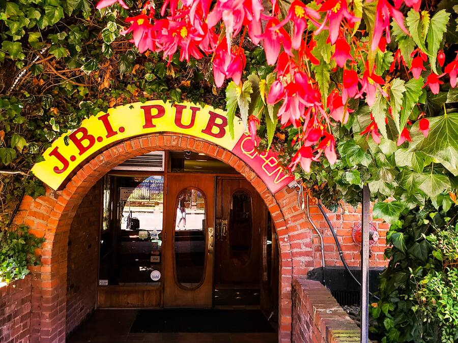An entrance to J.B.I. Pub with a brick archway and a sign above.