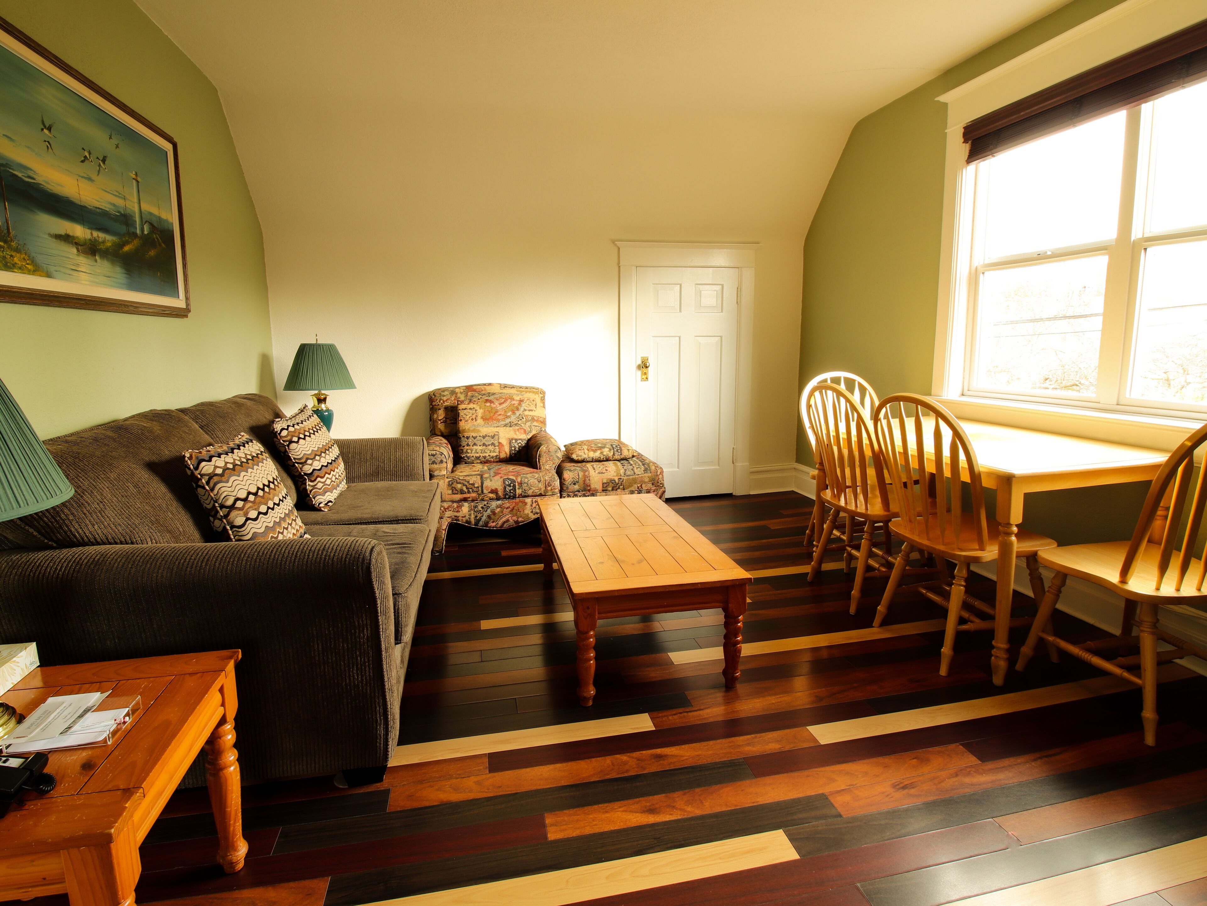 A cozy living room with a sofa, armchair, wooden coffee table, and dining table with chairs.