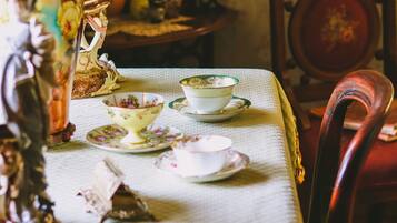 Una mesa de comedor con mantel, un florero con flores, y varios platos y tazas.