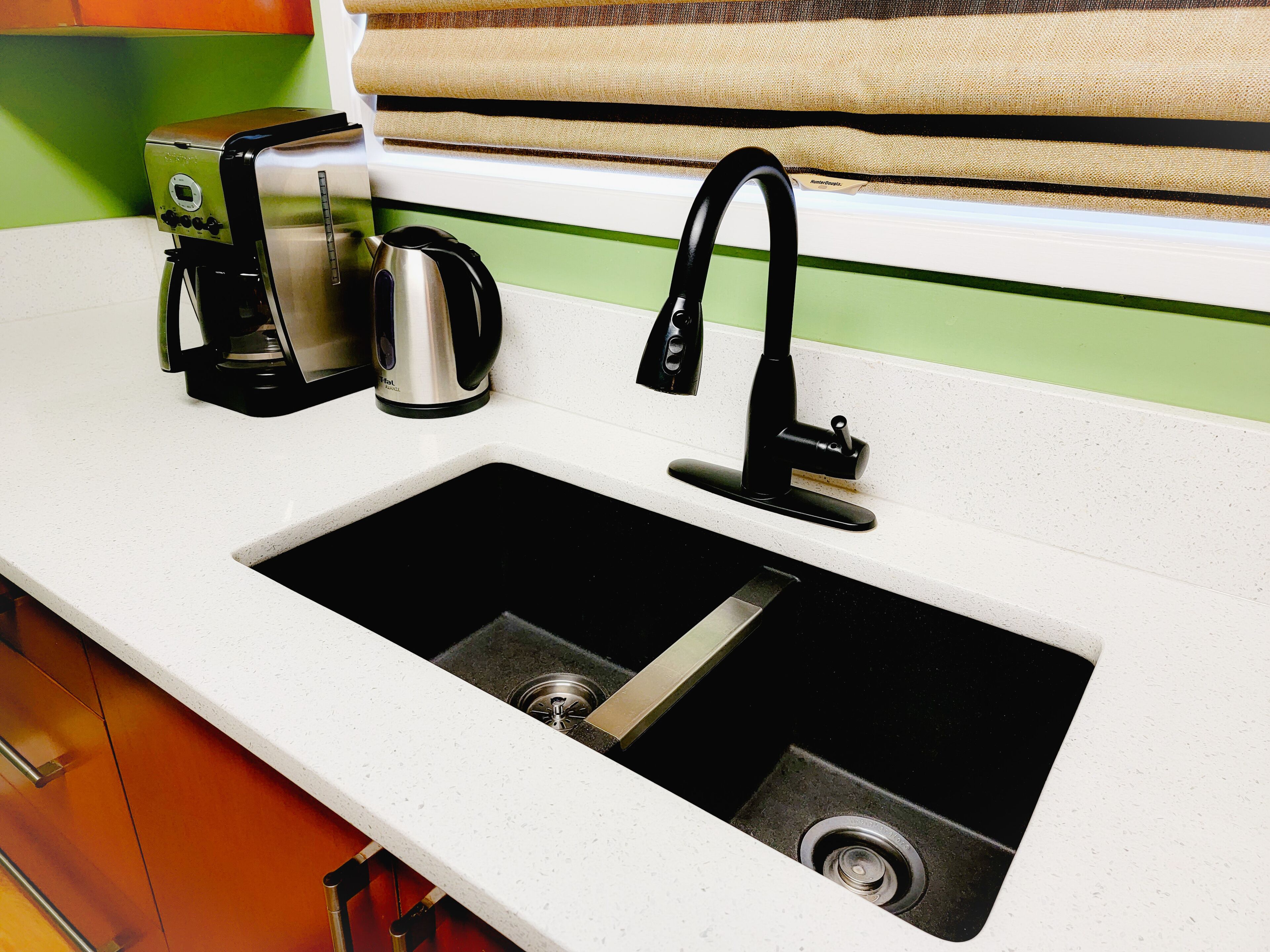 A kitchen with a sink, a coffee maker, and a kettle.