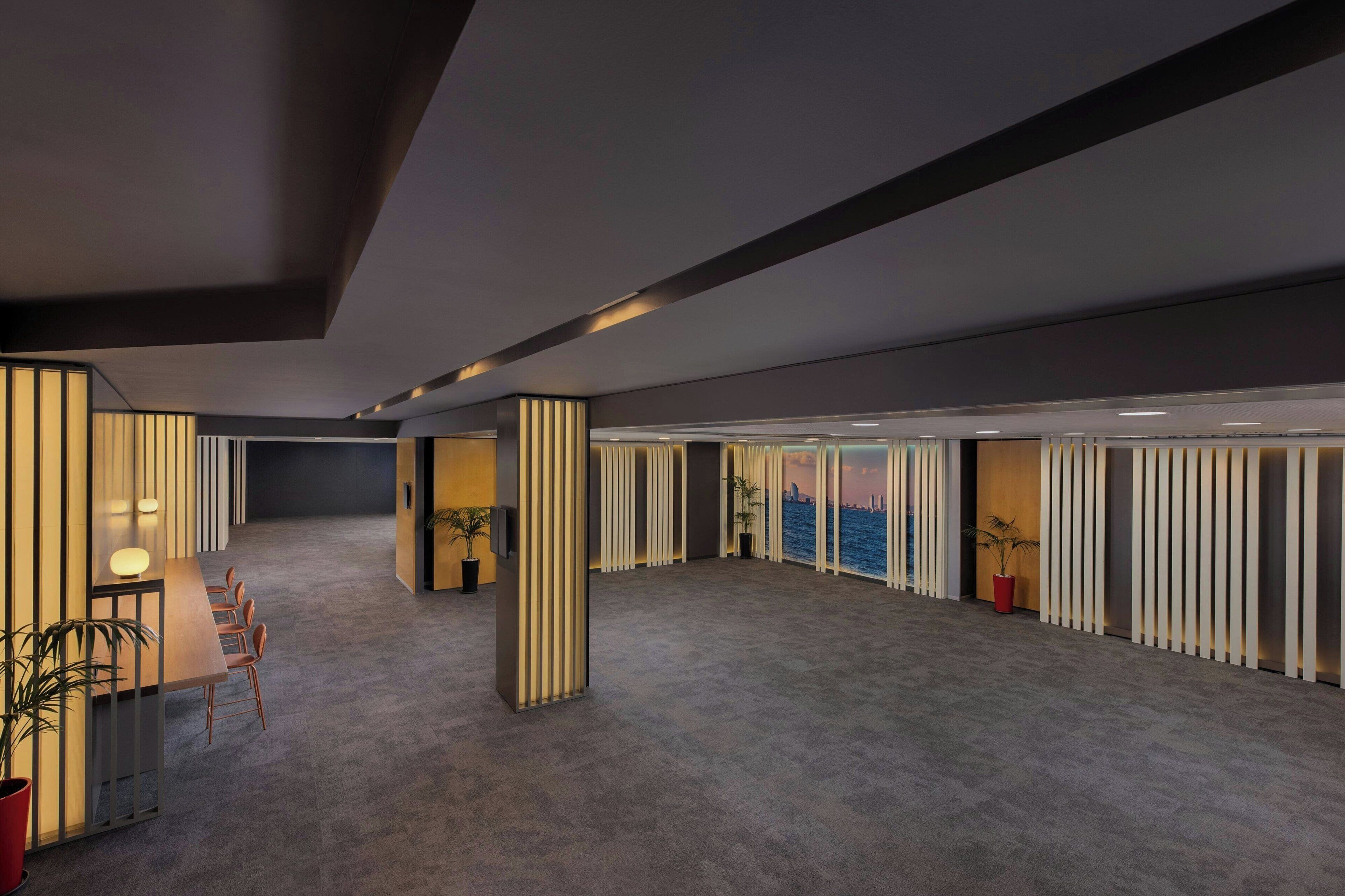 A spacious, modern hotel lobby with a large seating area, a view of the water, and a minimalist design.
