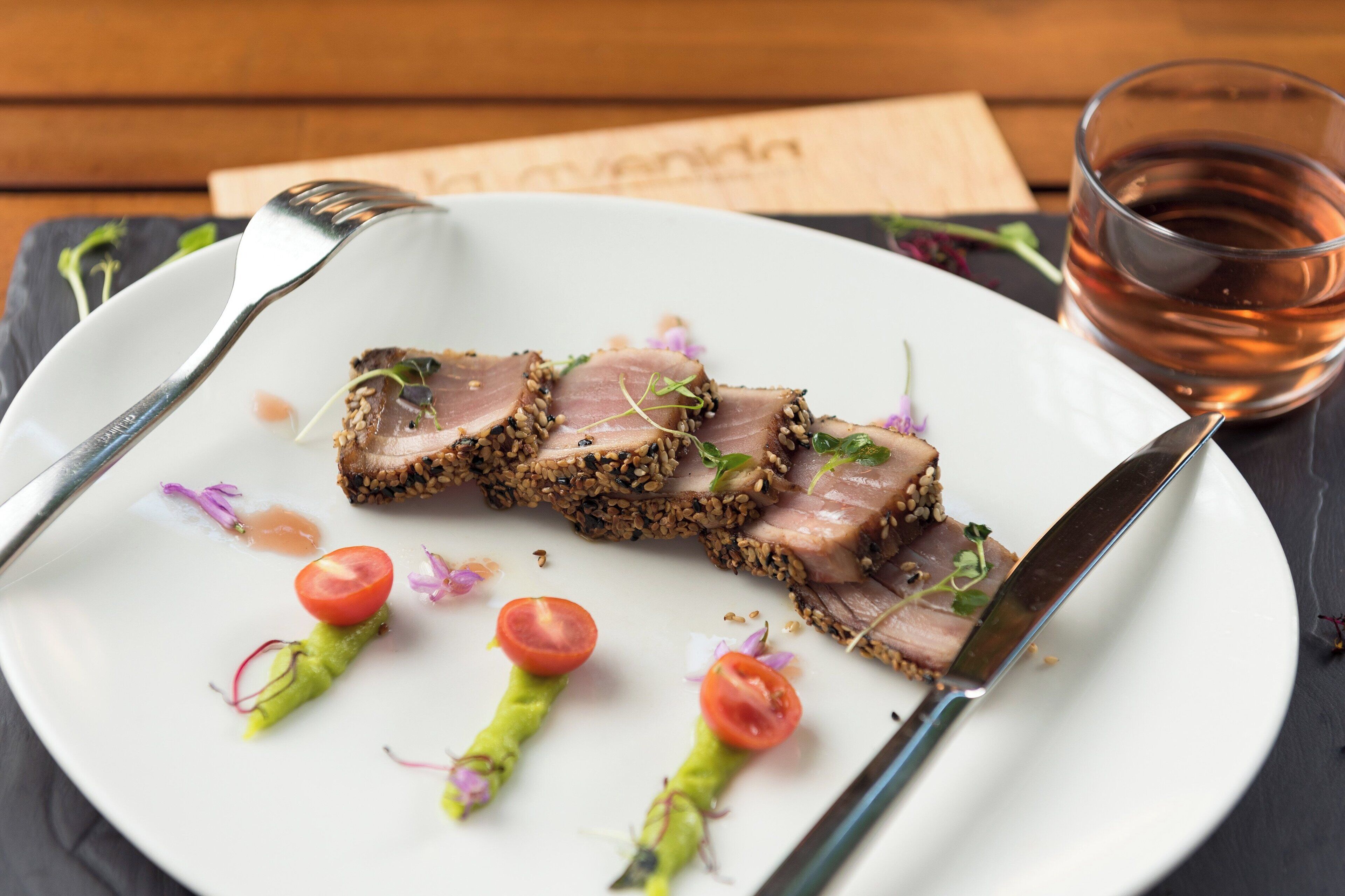 Un plato de comida con un tenedor, un cuchillo y una servilleta sobre una mesa de madera.