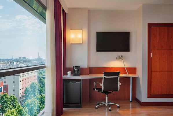 Una habitación de hotel moderna con un escritorio, una silla y un televisor de pantalla plana.