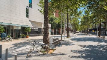 A modern building with a glass facade, a bicycle parked outside, and a bench in the foreground.