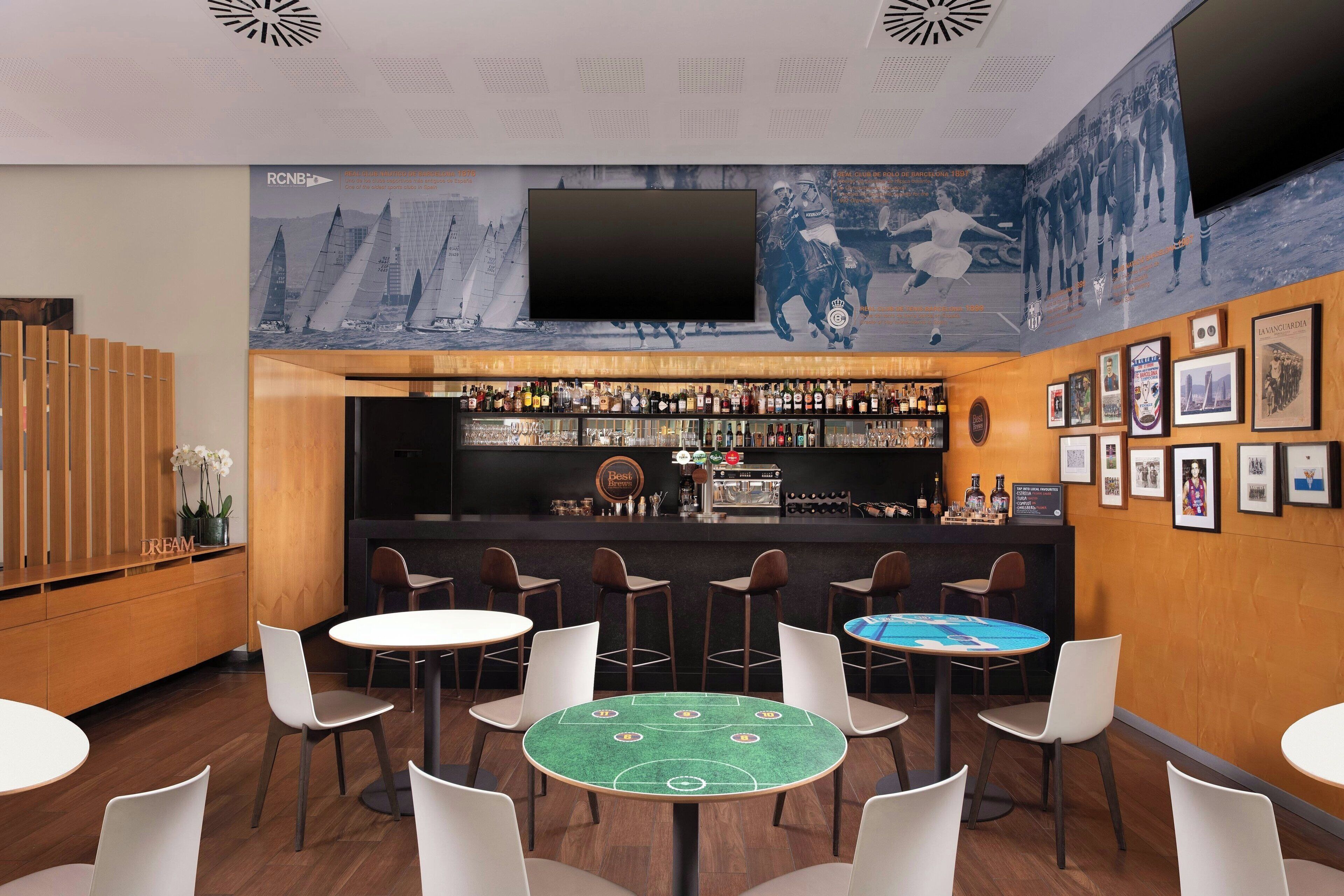 Una zona de bar con mostrador, taburetes y una mesa con mantel verde.