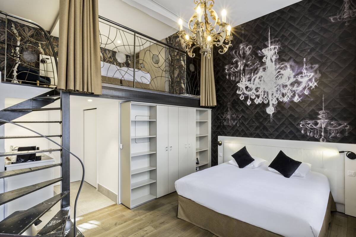 Un dormitorio con una cama grande, una araña, un armario y una escalera.