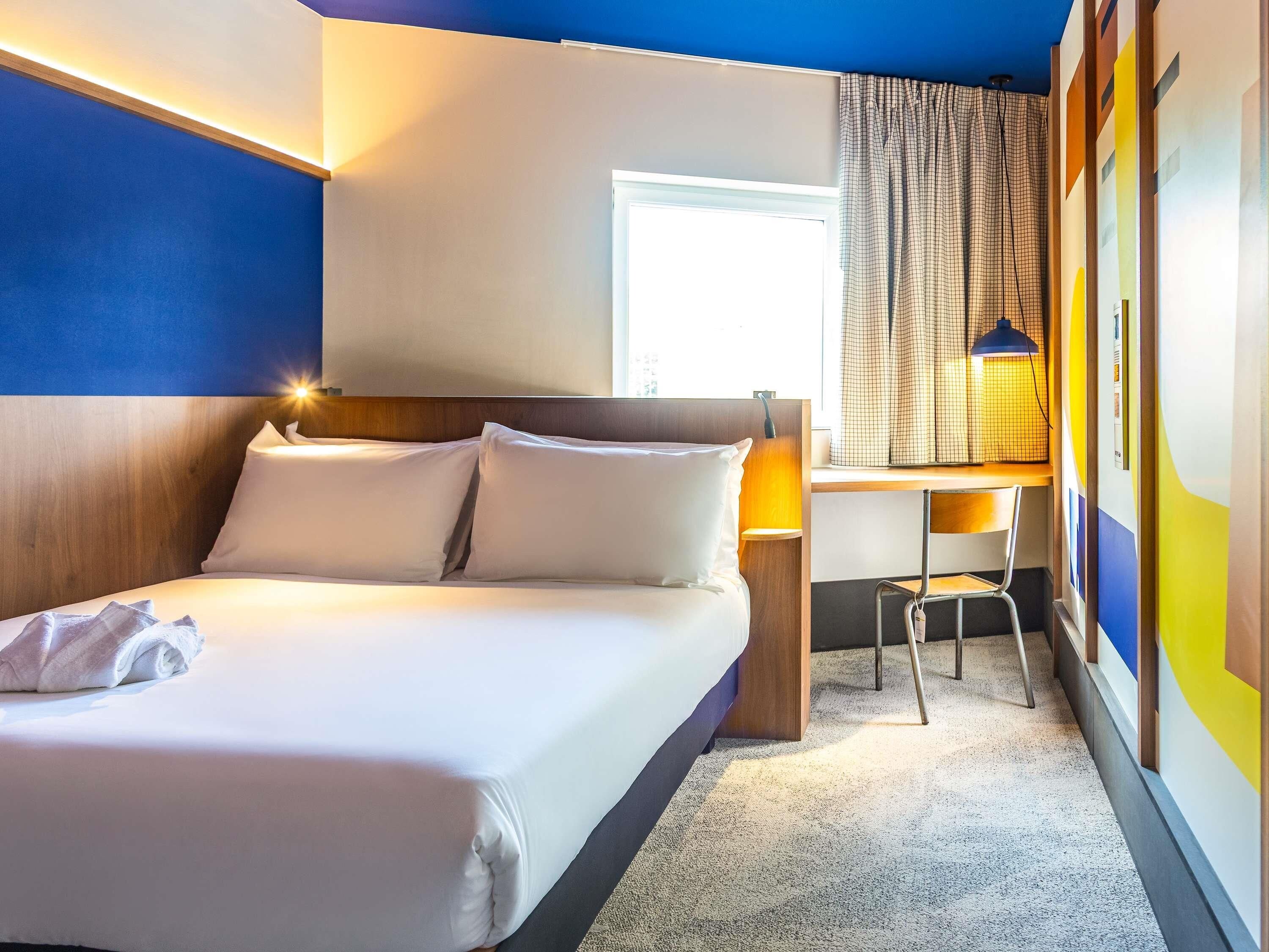 A hotel room with a bed, a desk, and a chair.