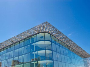 Un bâtiment moderne doté d’une façade en verre incurvée et d’une structure en treillis originale sur le toit.