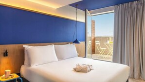 A hotel room with a large bed, a nightstand, a lamp, and a view of the outdoors. - greet hotel Marseille Parc Chanot Vélodrome by Accor (Marseille)