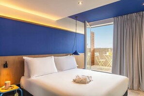 A hotel room with a large bed, a nightstand, a lamp, and a view of the outdoors. - greet hotel Marseille Parc Chanot Vélodrome by Accor (Marseille)