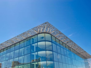 Un bâtiment moderne doté d’une façade en verre incurvée et d’une structure en treillis originale sur le toit.