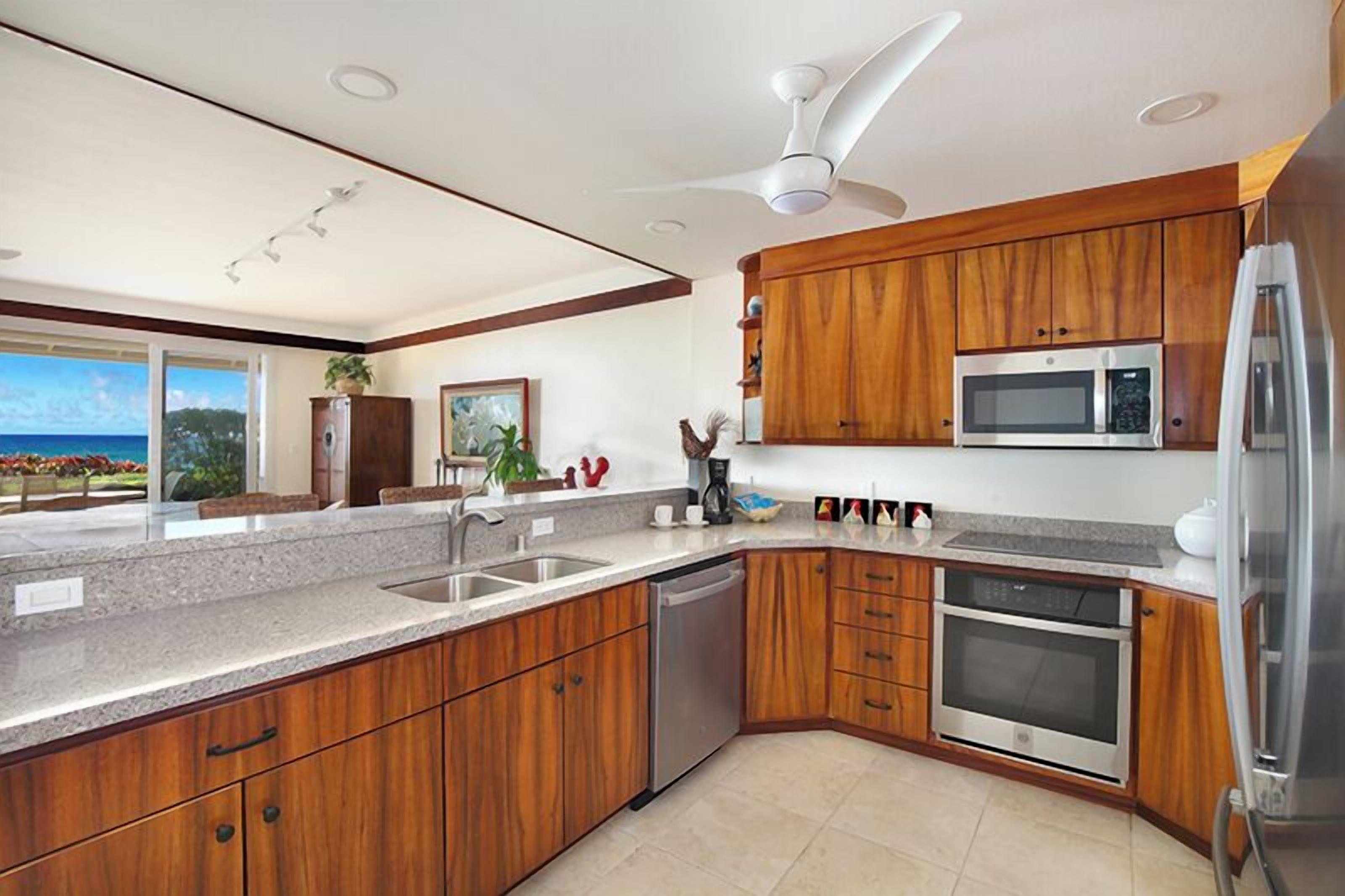 A modern kitchen with wooden cabinets, stainless steel appliances, and a large window overlooking a scenic view.