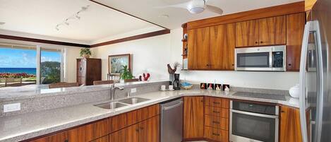 A modern kitchen with wooden cabinets, stainless steel appliances, and a large window overlooking a scenic view.