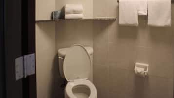 A bathroom with a toilet, a shelf with folded towels, and a towel rack.