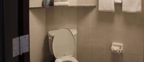 Un bagno con il water, uno scaffale con asciugamani piegati e un portascope.