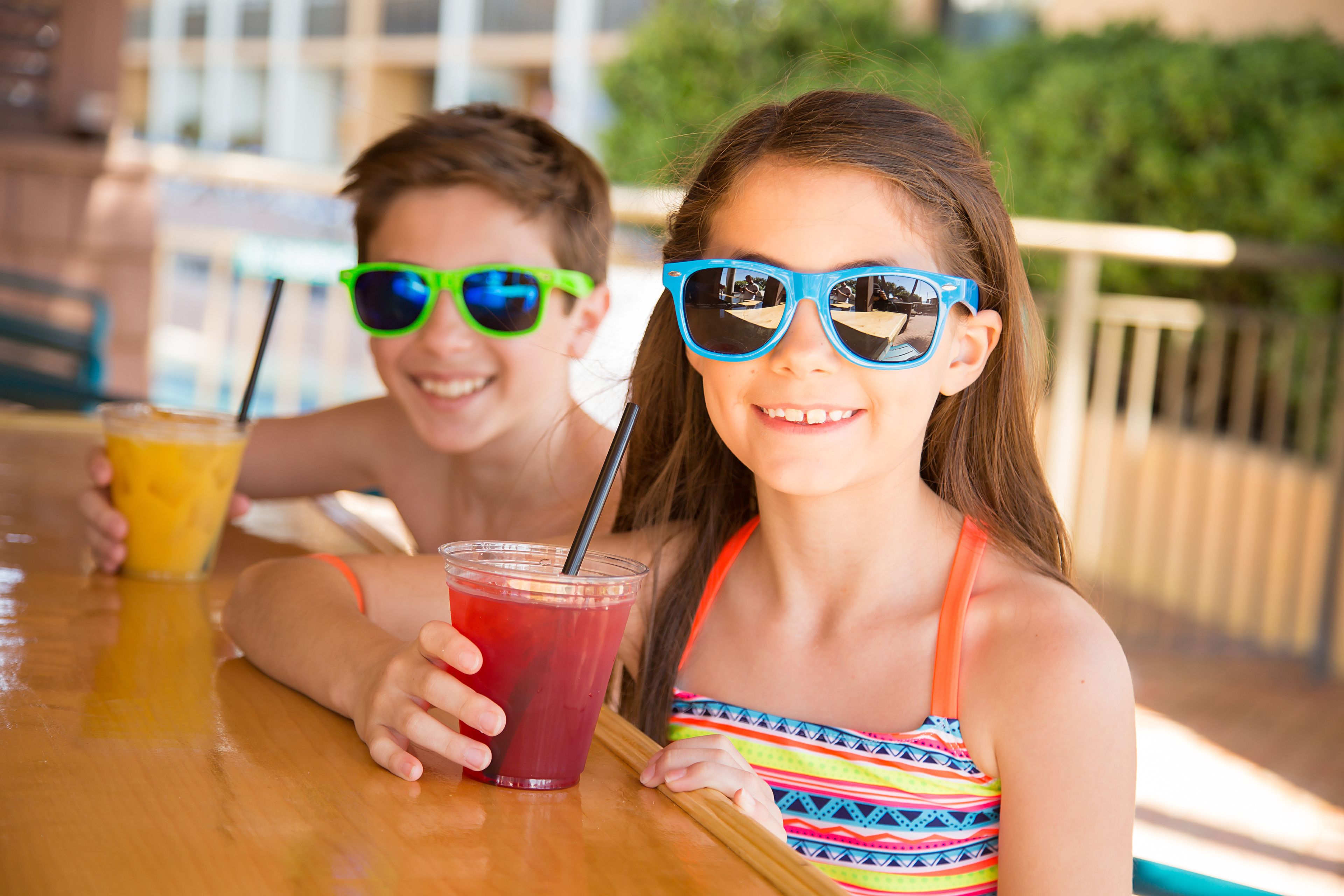 A wooden table with drinks and a person in a striped swimsuit.