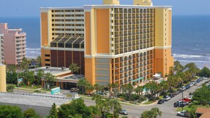 A multi-story hotel with a prominent glass facade, located near a beach with visible ocean views. - The Caravelle Resort (Myrtle Beach)