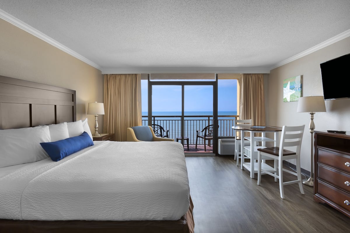 Una habitación de hotel con una cama grande, un escritorio y vista al océano.