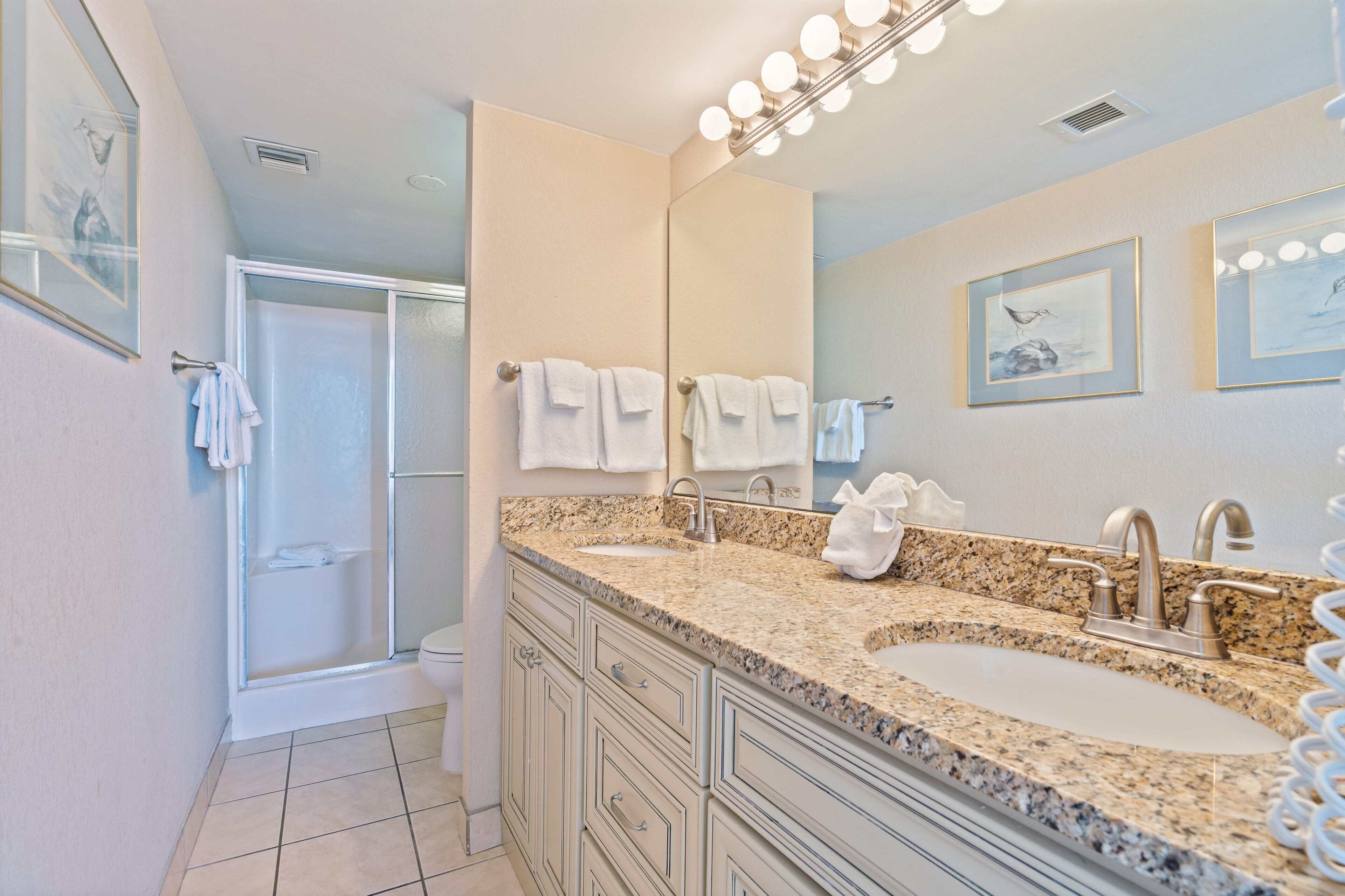 A bathroom with two sinks, a shower, and a large mirror.