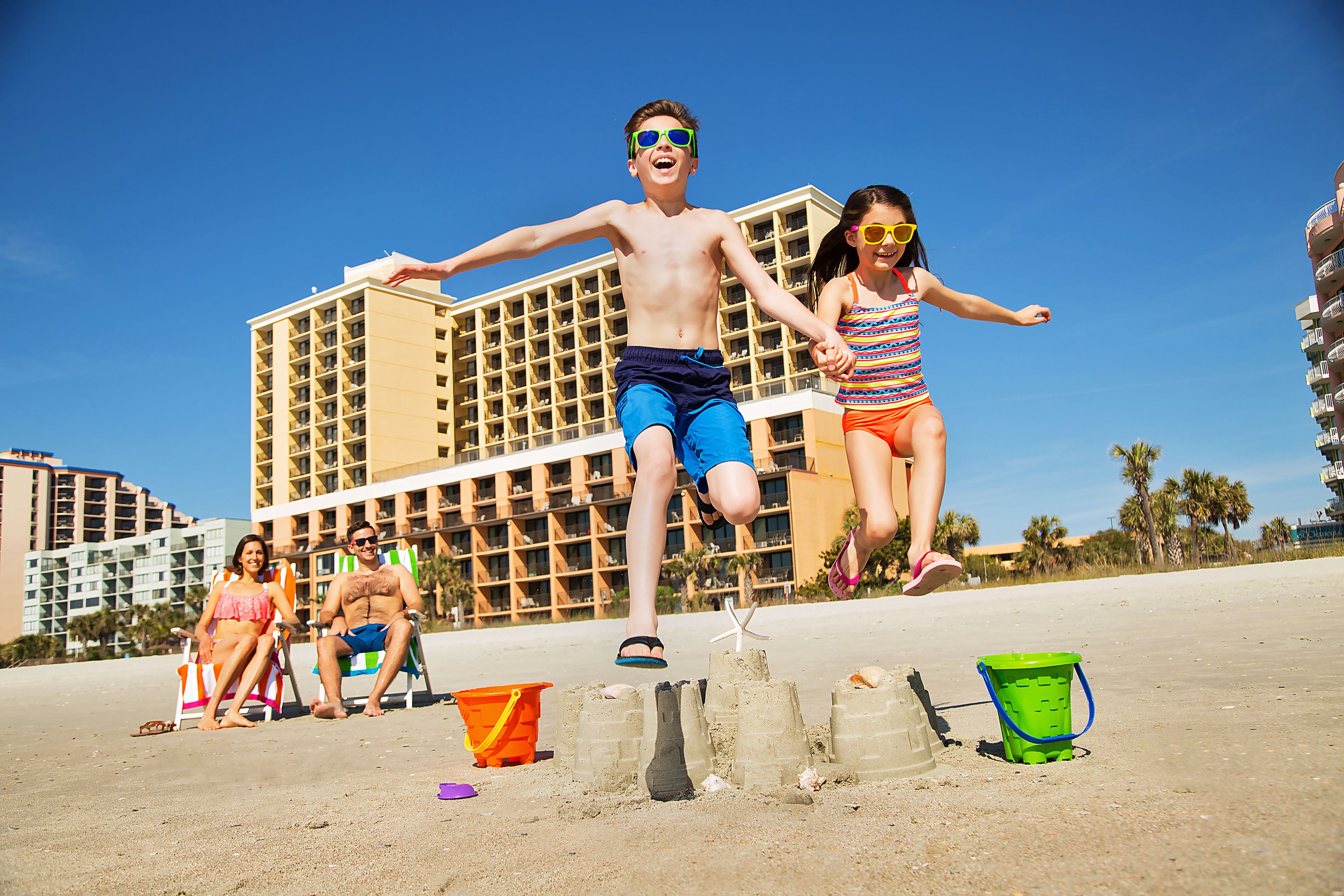 A beachfront hotel with multiple balconies and a sandy beach area.