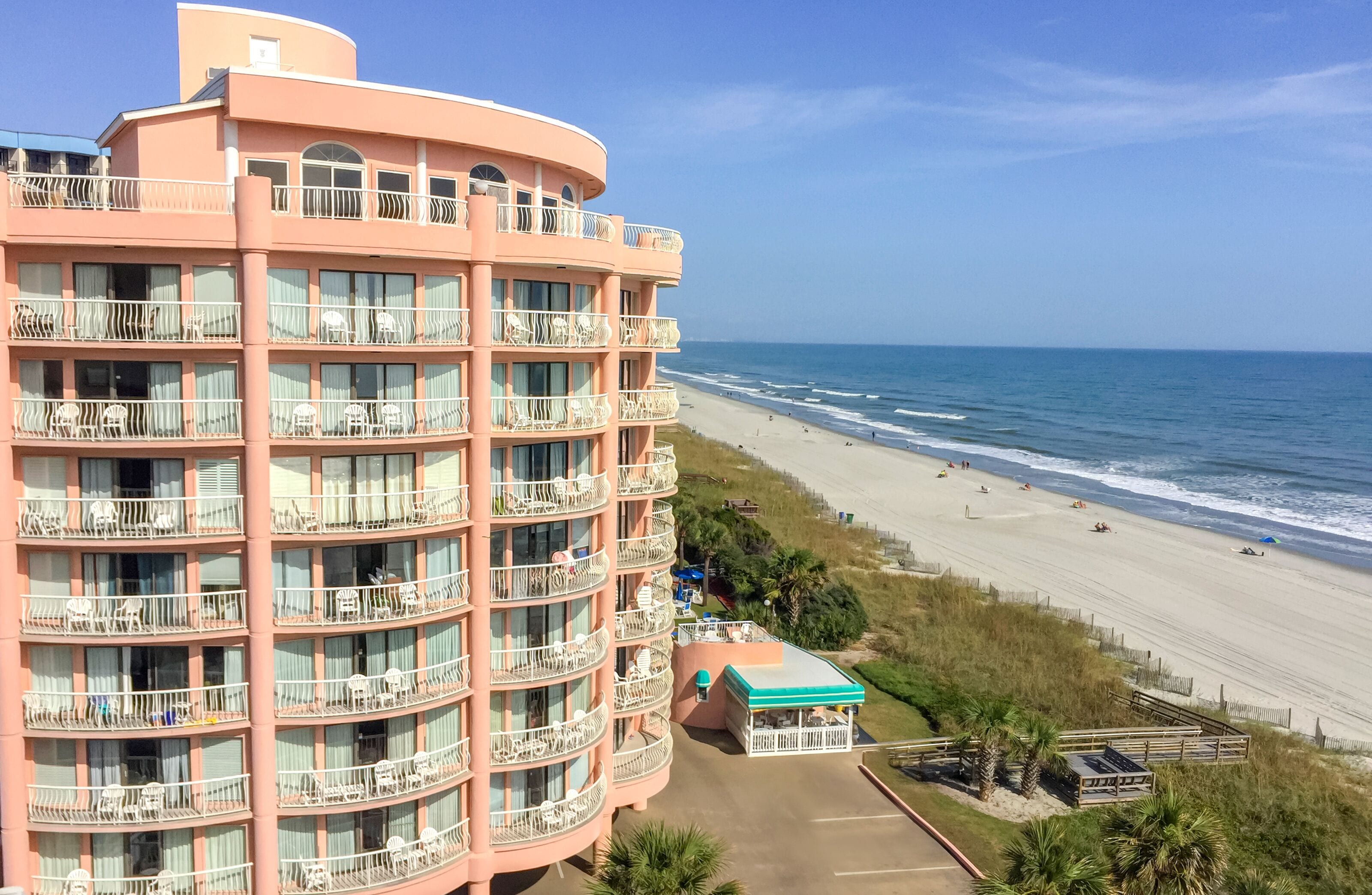 A multi-story hotel with balconies overlooking a beach.