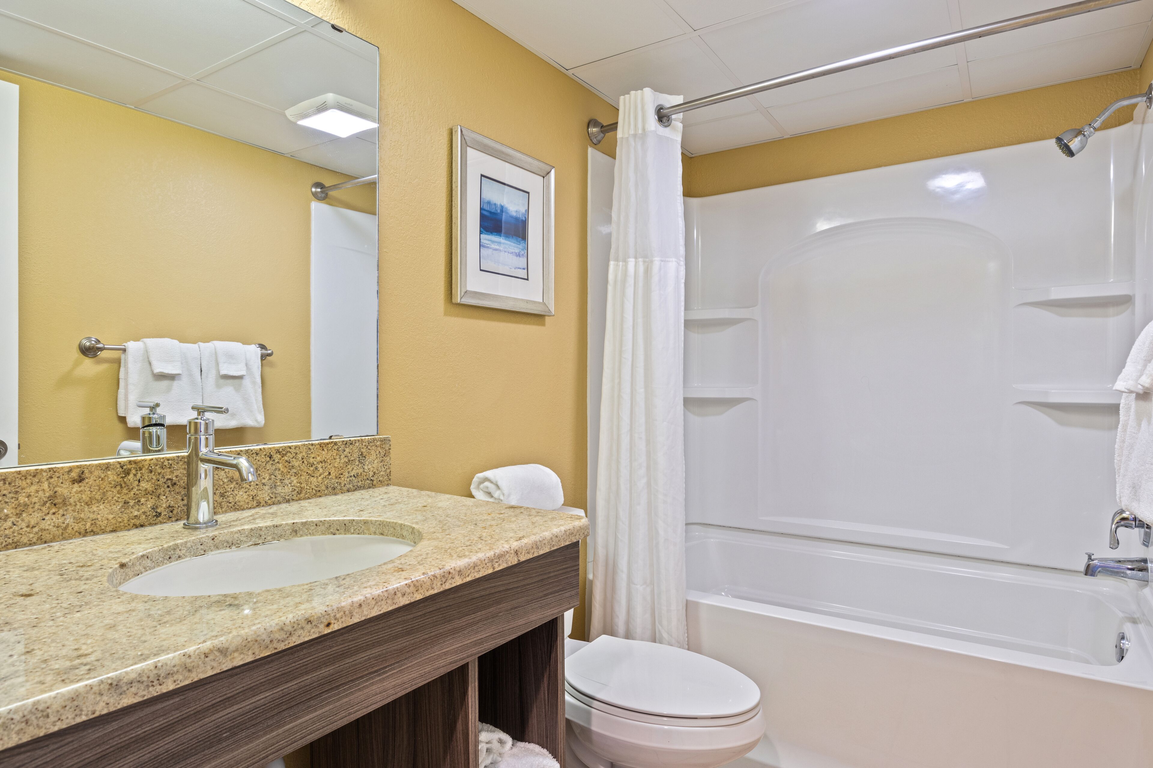 Un baño con lavabo, espejo, inodoro y bañera.