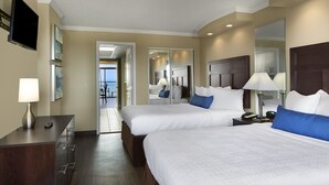 A hotel room with two beds, a desk, a TV, and a bathroom mirror. - The Caravelle Resort (Myrtle Beach)