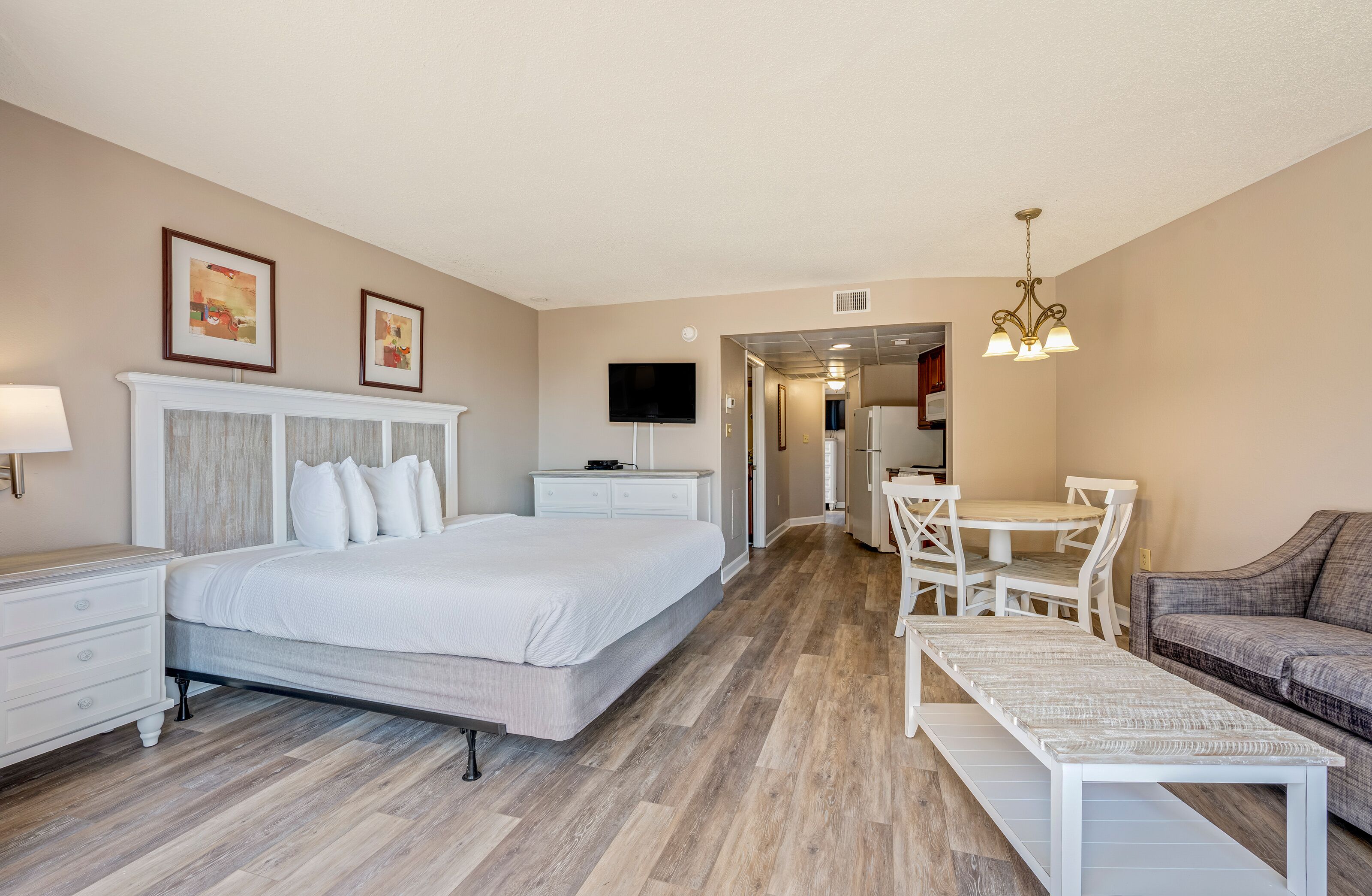 Ein Hotelzimmer mit Bett, Schreibtisch, Sessel, Sofa und Fernseher.