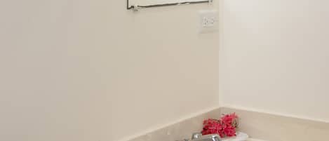 Un baño con un lavabo blanco, un espejo y un perchero para toallas.