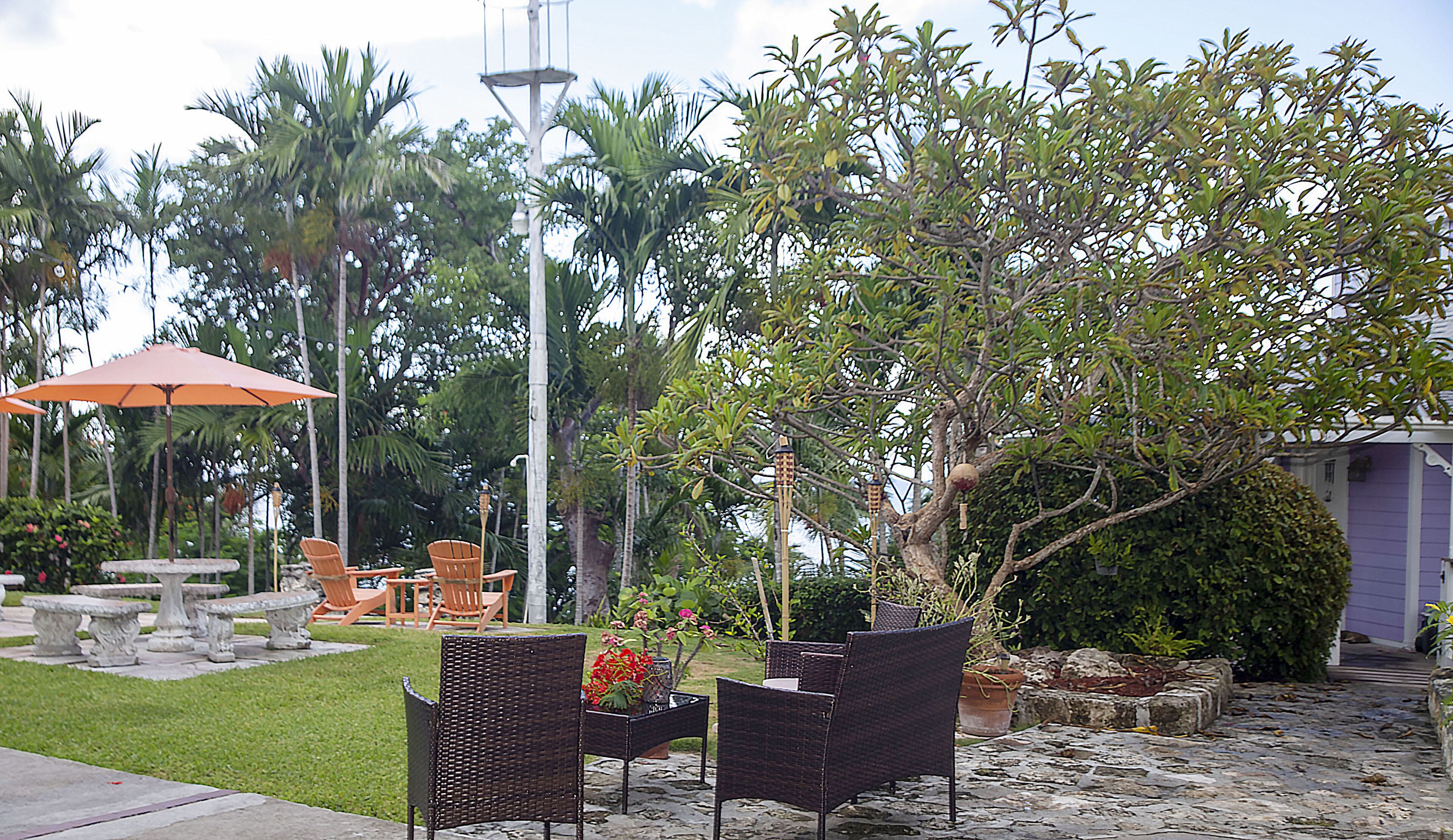 An outdoor patio area with wicker furniture, a stone table, and a red umbrella.