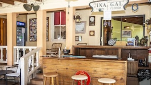 Uma área de bar com banquetas de madeira, balcão e um letreiro com a inscrição "TINA GAL TAMPA FLORIDA".