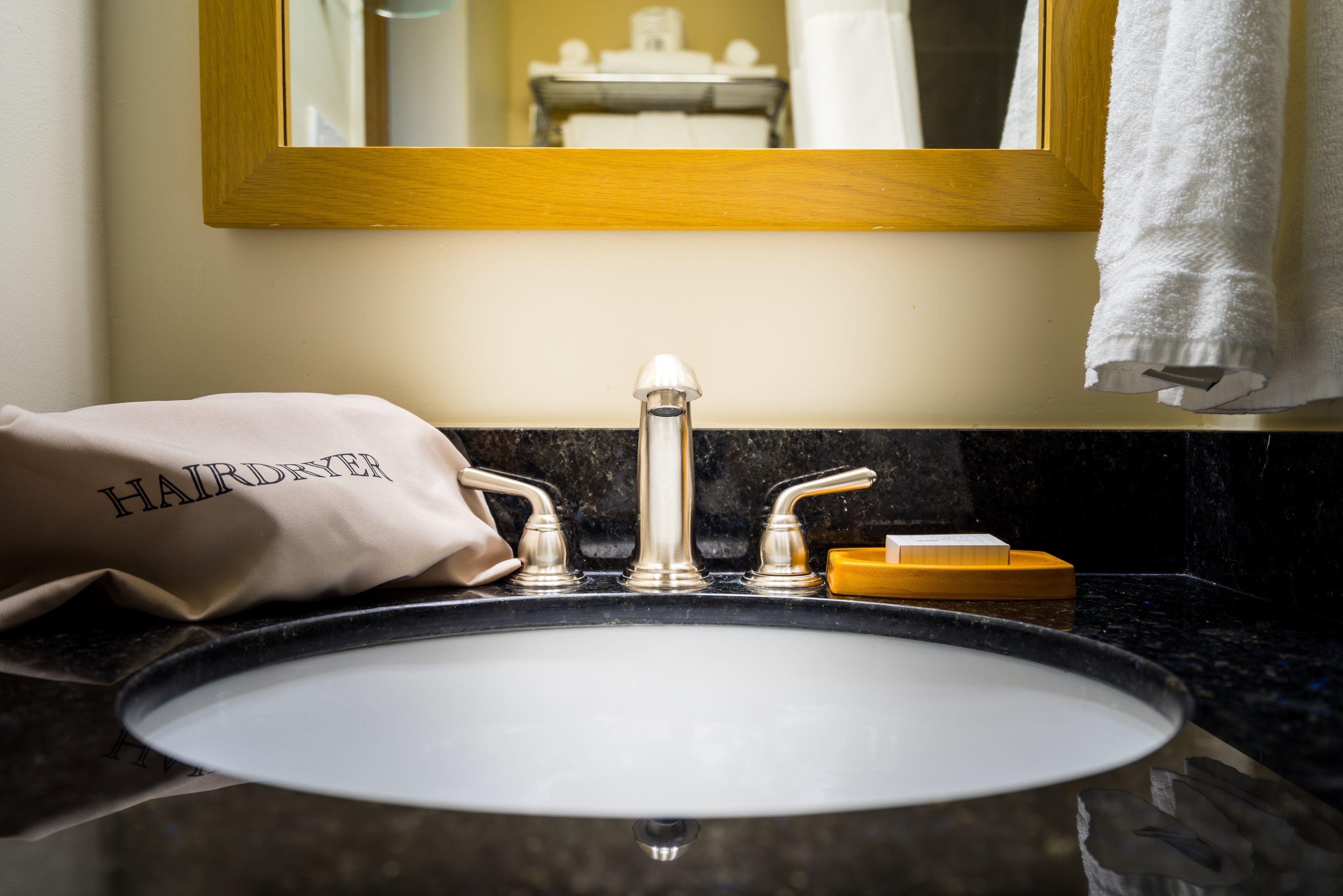 A bathroom sink with a gold faucet, a towel, and a soap dish.