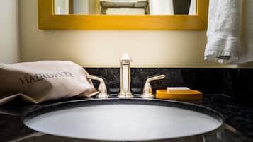 A bathroom sink with a gold faucet, a towel, and a soap dish.