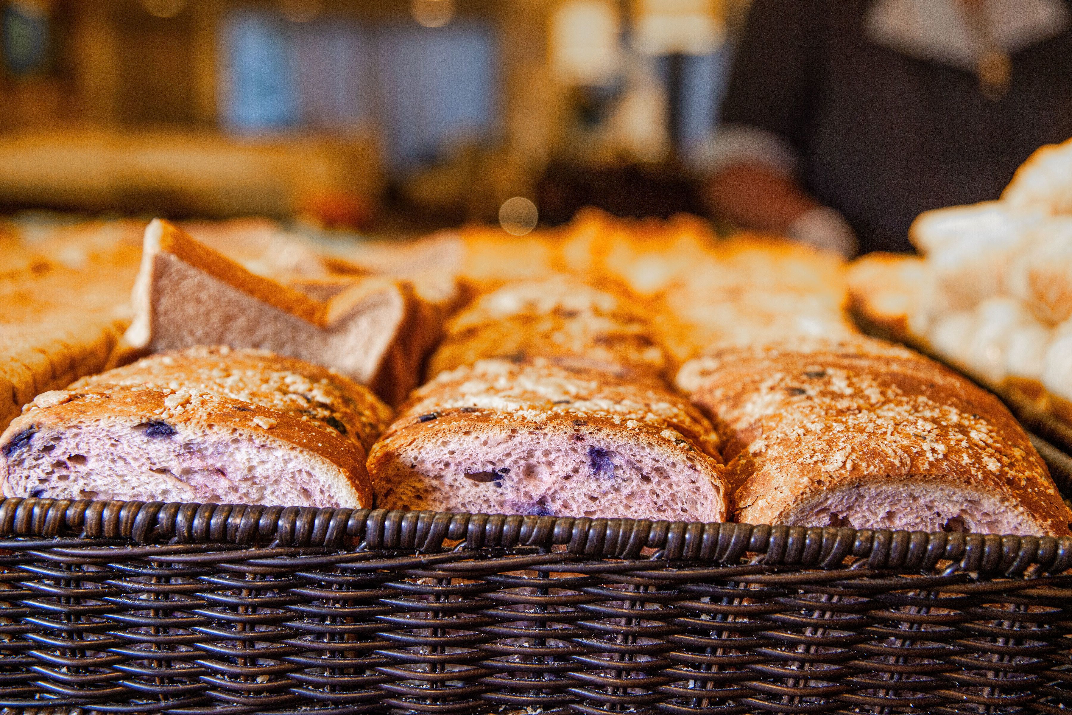 A basket of various breads, including a loaf with a distinctive triangular shape.