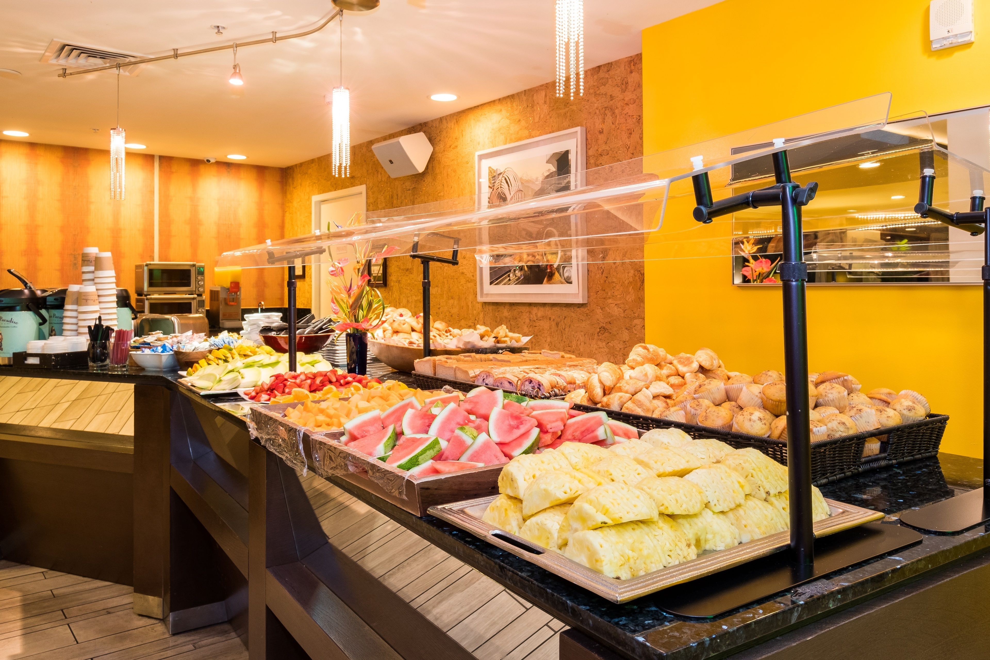 A buffet with various food items, including fruits, pastries, and sandwiches.