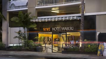 L’extérieur du VIVE HOTEL WAIKI se distingue par son design moderne, avec une structure à deux étages, une voiture visible au niveau supérieur et une entrée bien éclairée.