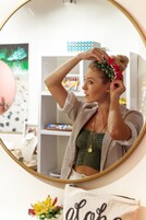 A person in a room with a mirror, shelves with items, and a wall with a geometric pattern.