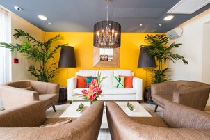 Um lobby moderno com um sofá branco, poltronas marrons e um grande candelabro.