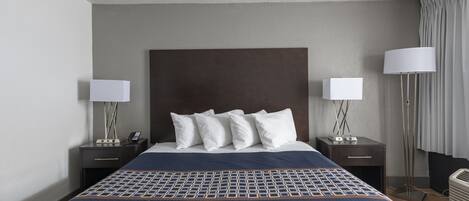 A hotel room with a large bed, two bedside tables with lamps, a headboard, and a floor lamp.