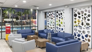 A modern lounge area with blue sofas, wooden tables, and a pool view.