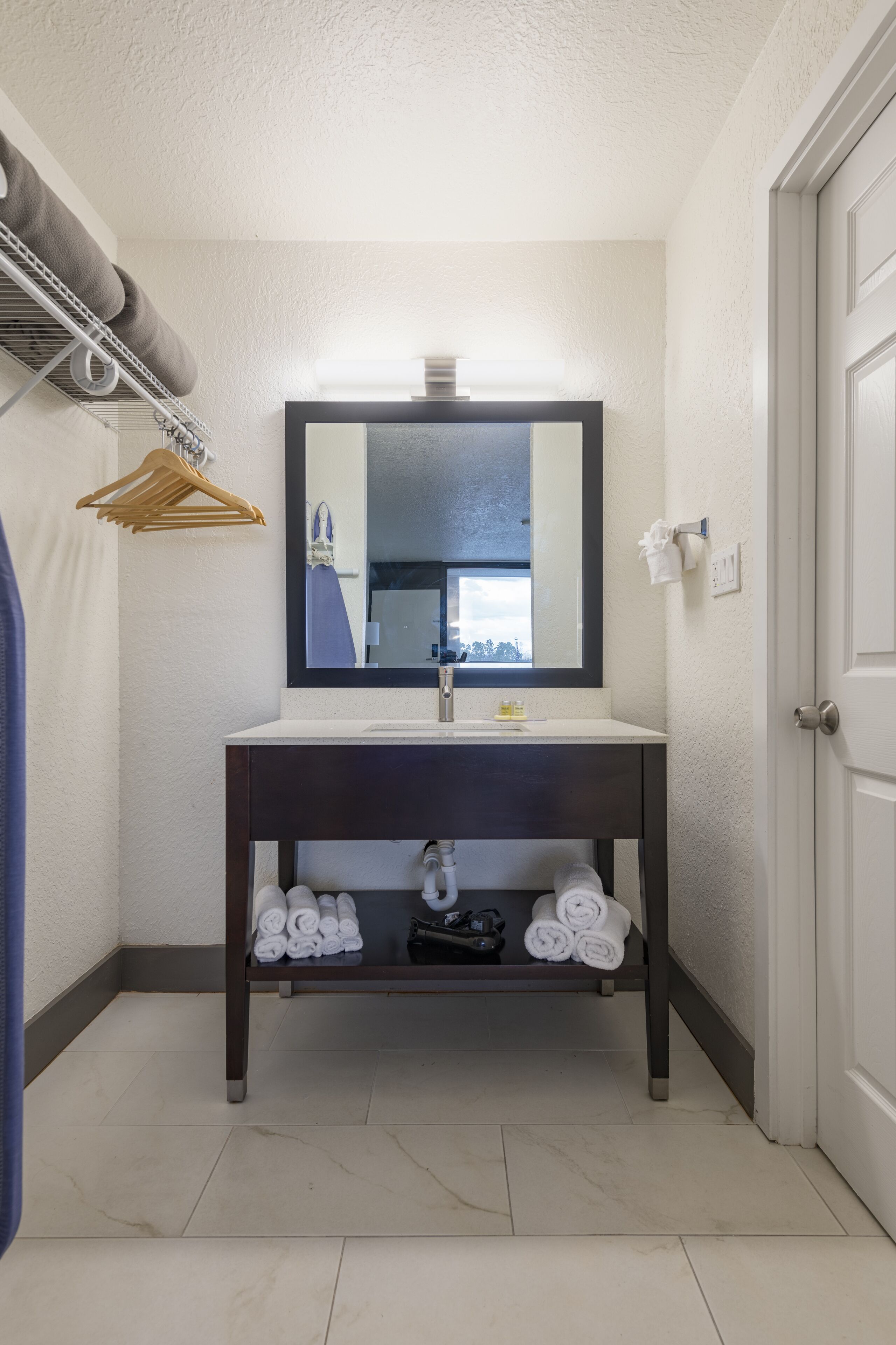A bathroom with a dark wooden vanity, a mirror, and a towel rack with towels.